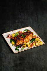 Grilled chicken with sauce on stone plate.