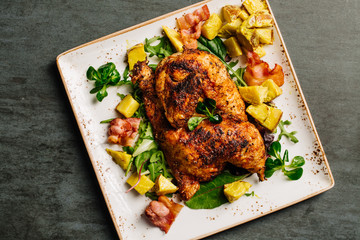 Grilled chicken with sauce on stone plate.