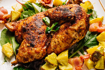 Grilled chicken with sauce on stone plate.