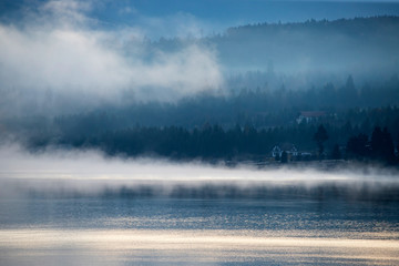 Lovely autumnal landscape with fog over the lake.