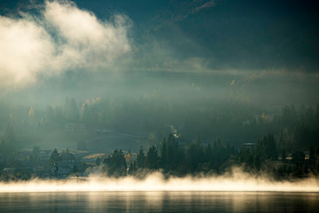 Lovely autumnal landscape with fog over the lake.