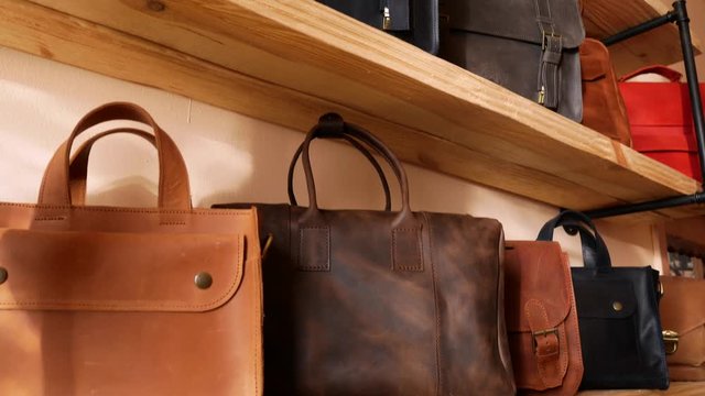 Bags show room. Genuine leather bags on the shelf. Tilt panoramic move 4k
