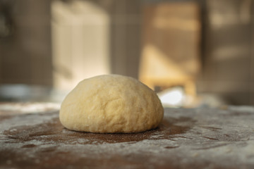 Ball of dough lying on a wooden table in the kitchen