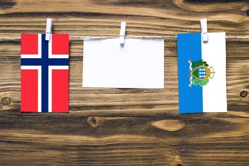 Hanging flags of Bouvet Islands and San Marino attached to rope with clothes pins with copy space...