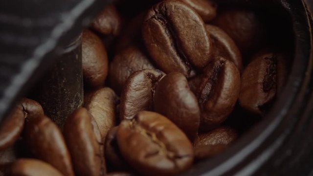 Close up of a coffee bean grinder opening and coffee beans being being dropped in