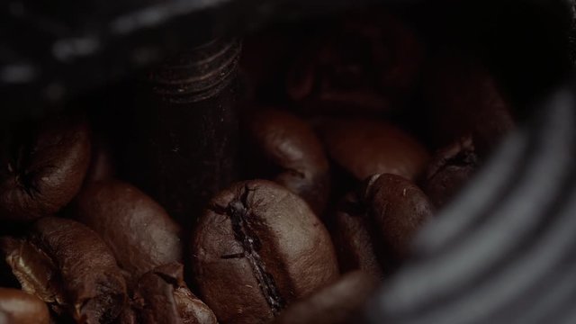 Extreme close up of a metal hand grinder being opened revealing fresh coffee beans