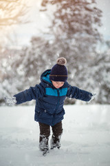 Adorable, cute boy playing with snow cheerfully