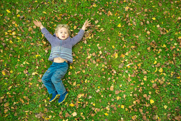 Un petit garçon étendu sur l'herbe avec des feuilles mortes