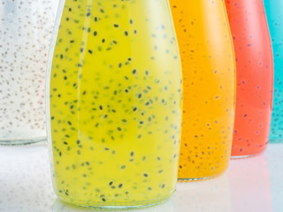 Close up view of bottles of Basil Seed beverage. Red, yellow, light blue and green color. Soft focus.