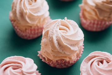 pink muffins with cream on a dark green background