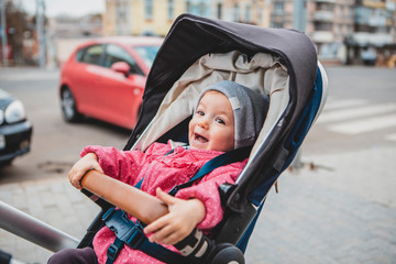 happy and cheerful child is having fun sitting in a stroller while walking with his parents
