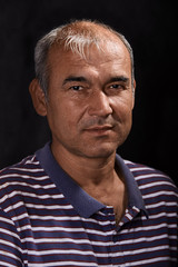 Portrait of a young tanned Asian man on a black background