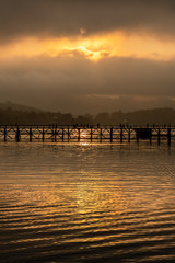 Fototapeta premium Old wooden bridge over the river (Mon Bridge) in sunrise at Sangkhla Buri District, Kanchanaburi, Thailand.