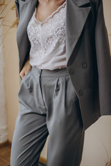 Portrait of an attractive blonde woman poses for the advertisement of a women's clothing store dressed in a gray jacket and pants with a blouse