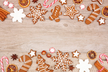 Christmas gingerbread cookies, candy and baking items. Top view double border on a wood background.