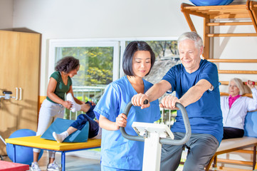 Senior retired elderly people in sports clothing in gym, working out with the help of trainer