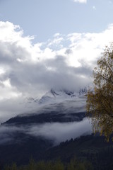 beautiful view to the alps with fog, clouds and fresh snow on the mountains in autumn