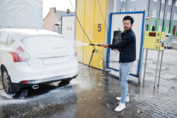 South asian man or indian male washing his white transportation on car wash.
