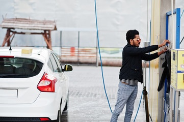 South asian man or indian male washing his white transportation on car wash.