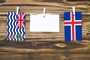 Hanging flags of British Indian Ocean Territory and Iceland attached to rope with clothes pins with...