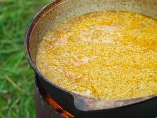 Cooking golden rice in nature, in a large aluminum bowl