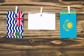 Hanging flags of British Indian Ocean Territory and Kazakhstan attached to rope with clothes pins...
