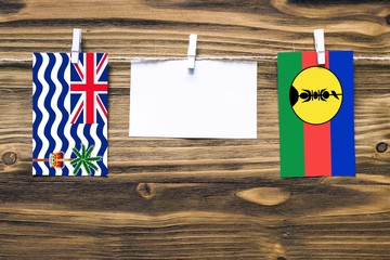 Hanging flags of British Indian Ocean Territory and New Caledonia attached to rope with clothes...
