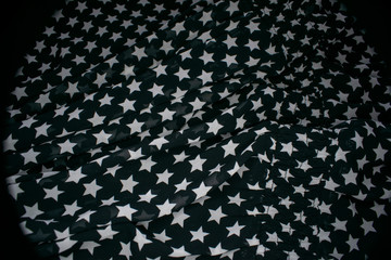 Fabric with the image of white stars on a black background, slightly crumpled.