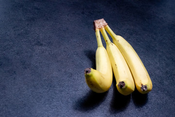 Tre banane su sfondo grigio blu