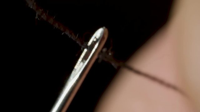 Man is trying to thread through the eye of a needle in macro