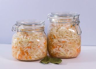 Sauerkraut, fermented cabbage in a glass jar on a gray background