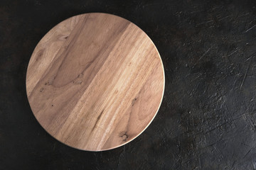 Round wooden cutting Board on the concrete to the abstract background.