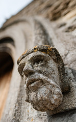 Stonework gargoyle in the shape of a kings head seen at the entrance to an old church.
