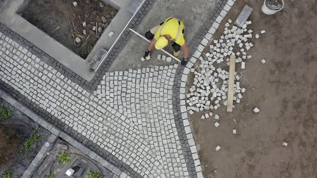 Residential Granite Brick Paving by Caucasian Construction Industry Worker. Aerial Footage.