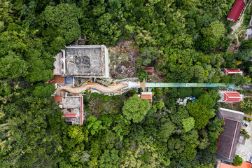 Dragon statue with temple and red shrine on hill in tropical rainforest at Wat Ban Tham