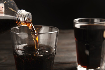 Pouring refreshing soda drink into glass on table, closeup. Space for text