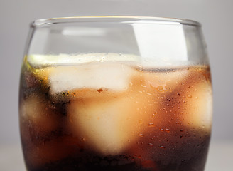 Glass of refreshing soda drink with ice cubes on grey background, closeup