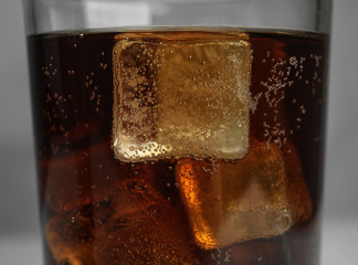 Glass of refreshing soda drink with ice cubes on grey background, closeup