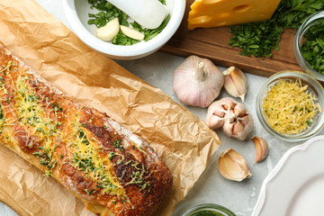Tasty homemade garlic bread with cheese and herbs on grey table, flat lay