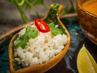 A plate of delicious pumpkin soup, a serving of rice with herbs and a slice of lime. On craft dishes