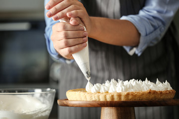Woman preparing lemon meringue pie in kitchen, closeup