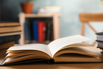 Open hardcover book on wooden table indoors. Space for text