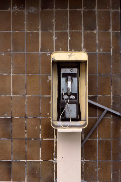Payphone next to brown tiled wall