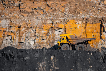Big yellow mining truck laden anthracite moves open pit coal mine