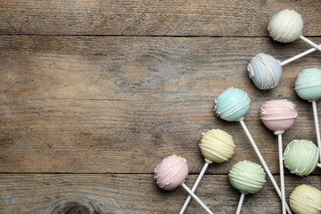 Sweet cake pops on wooden background, flat lay. Space for text
