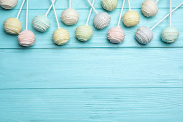 Fototapeta na wymiar Sweet colorful cake pops on turquoise wooden background, flat lay. Space for text