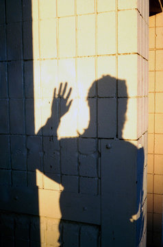 Silhouette of person waving on tile wall