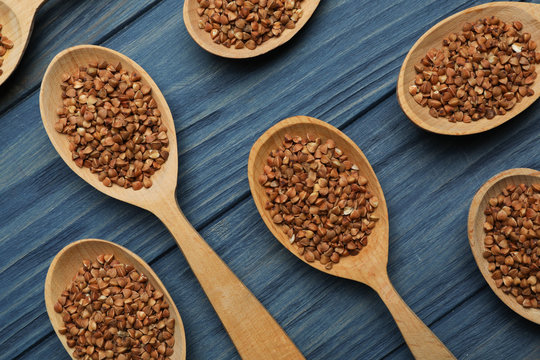 Buckwheat grains in spoons on blue wooden table, flat lay © New Africa