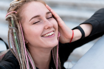 portrait of a beautiful young laughing woman with blond hair and african pigtails and dreadlocks