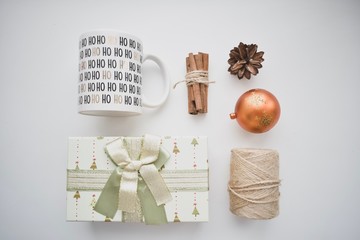 Christmas composition. Christmas gift, pine cones, mug with the text Ho Ho Ho, cinnamon, candle, Christmas tree toys on a white background. Flat sunbed, top view, copy space. Christmas background.
